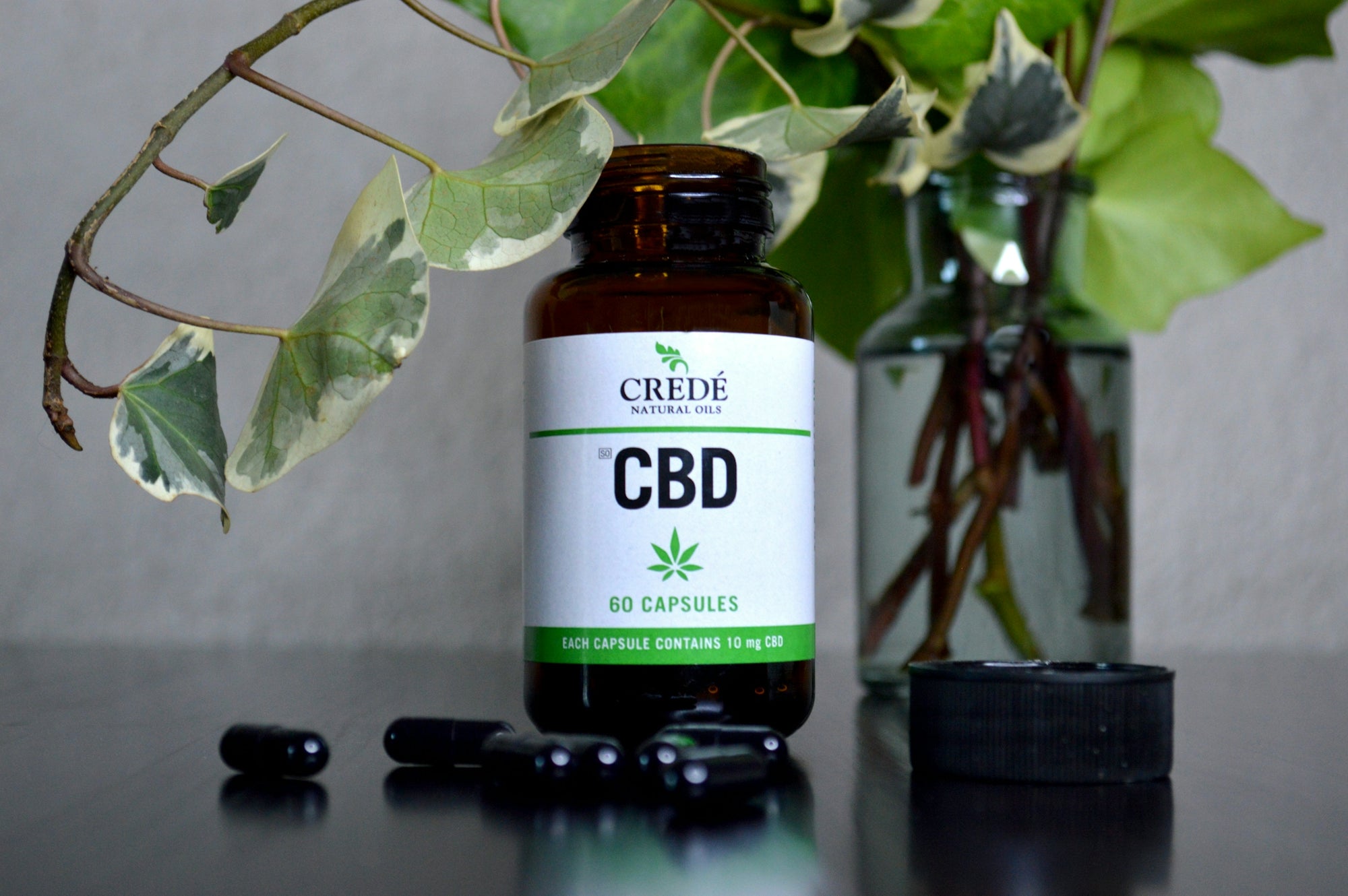 a bottle of cbd sitting next to a vase of flowers