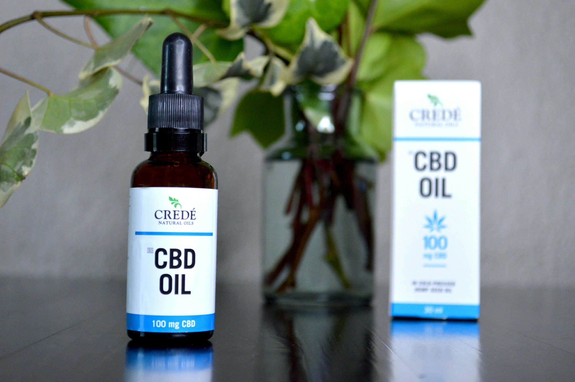 a bottle of cbd oil next to a vase of flowers